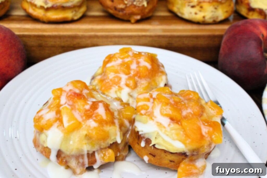 Three gooey, golden-brown air fryer Crown Royal peach cinnamon rolls on a plate, glistening with topping and frosting.