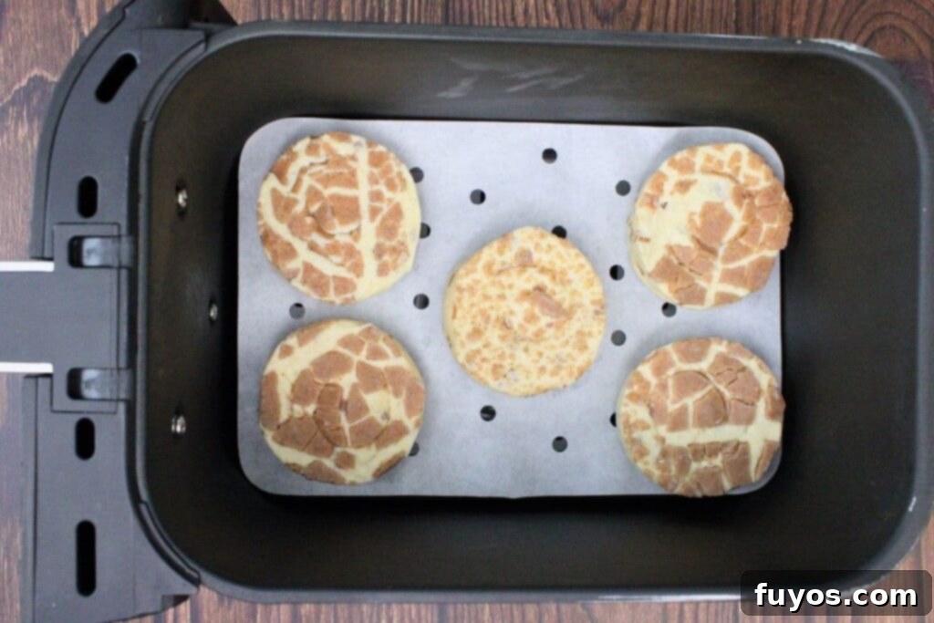 Pillsbury cinnamon rolls arranged in a single layer inside an air fryer basket, ready for cooking.
