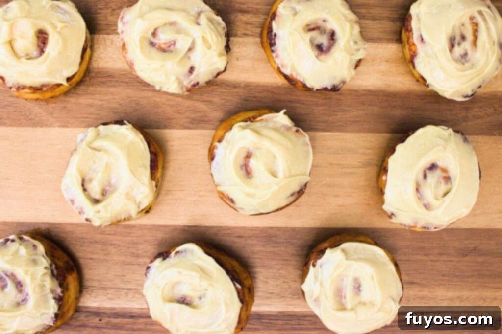 Warm cinnamon rolls with caramel icing spread over them, ready for the peach topping.