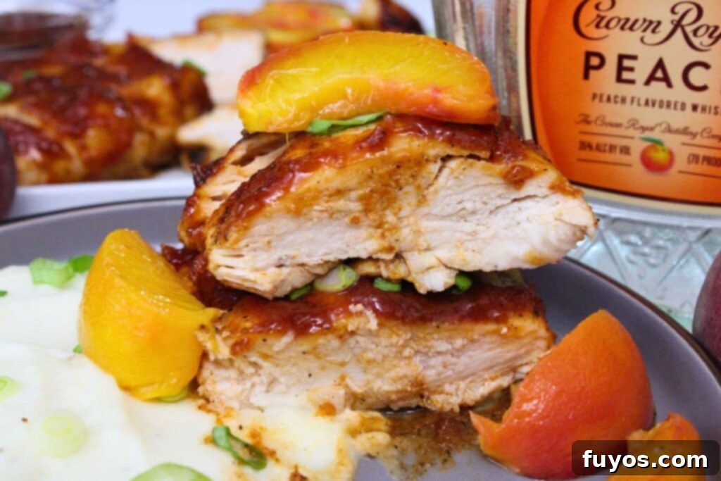 Simple Air Fryer Peach Whiskey BBQ Chicken Recipe 3 Two slices of tender peach whiskey BBQ chicken breast, garnished with a fresh peach slice, showcasing the succulent texture and flavorful glaze.