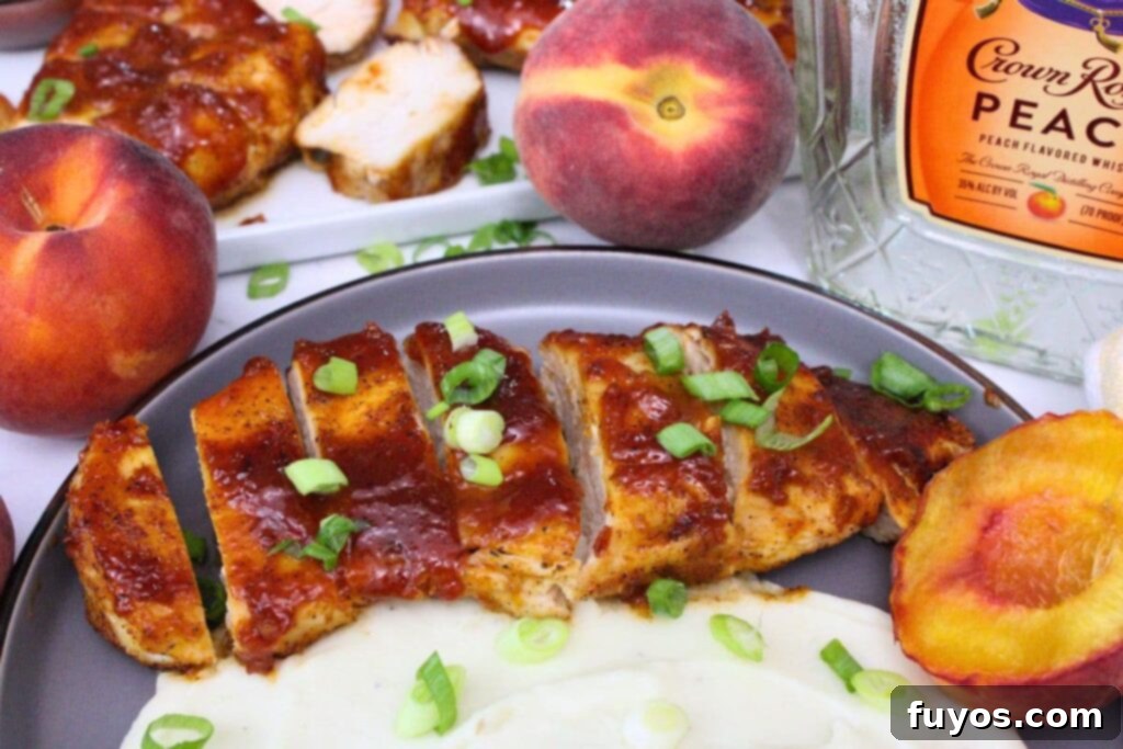 Simple Air Fryer Peach Whiskey BBQ Chicken Recipe 10 Slices of peach whiskey BBQ chicken breast elegantly spread on a plate, accompanied by a spoonful of mashed potatoes and a vibrant green garnish.