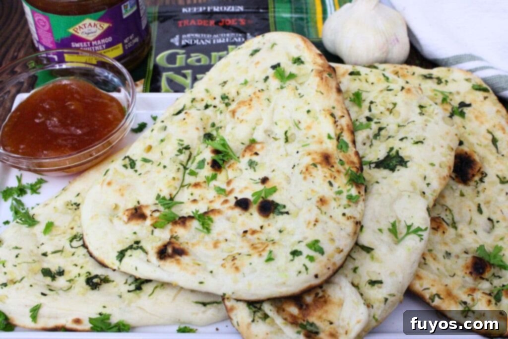 Four slices of air-fried Trader Joe's garlic naan arranged appealingly on a plate with a side of mango chutney dipping sauce.