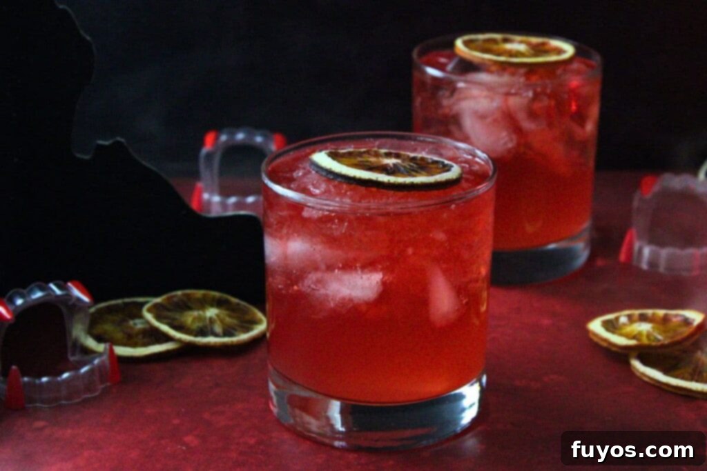 Blood Moon Rum Potion Zesty Halloween Brew 3 two blood moon cocktails with dried blood orange slices and fake vampire fangs, perfect for a Halloween party