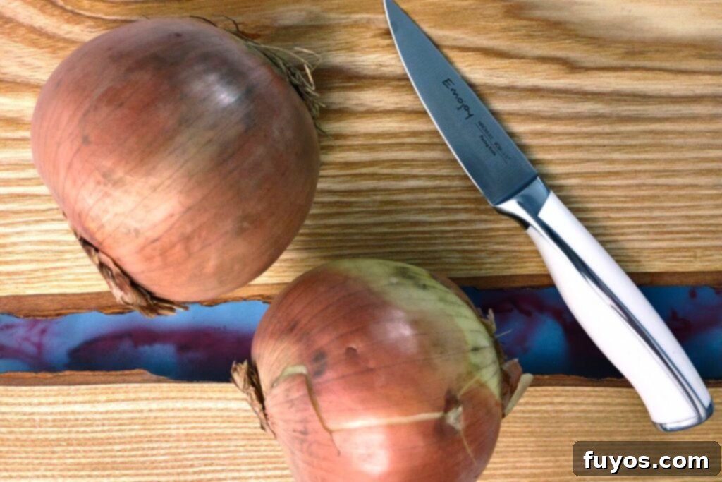 Air Fryer Caramelized Onions Made Easy 4 Two whole onions on a cutting board with a knife, ready for slicing