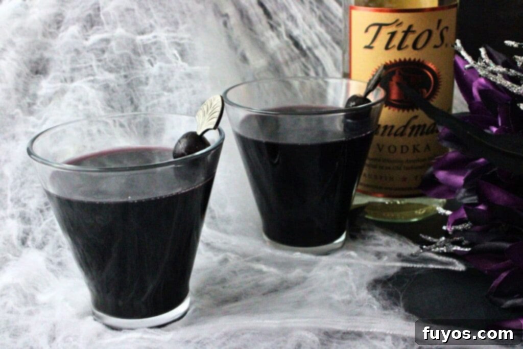Black Magic Martini: Halloween's Darkest Spell 3 two black martini drinks on wispy spiderwebs with a vodka bottle and halloween bouquet