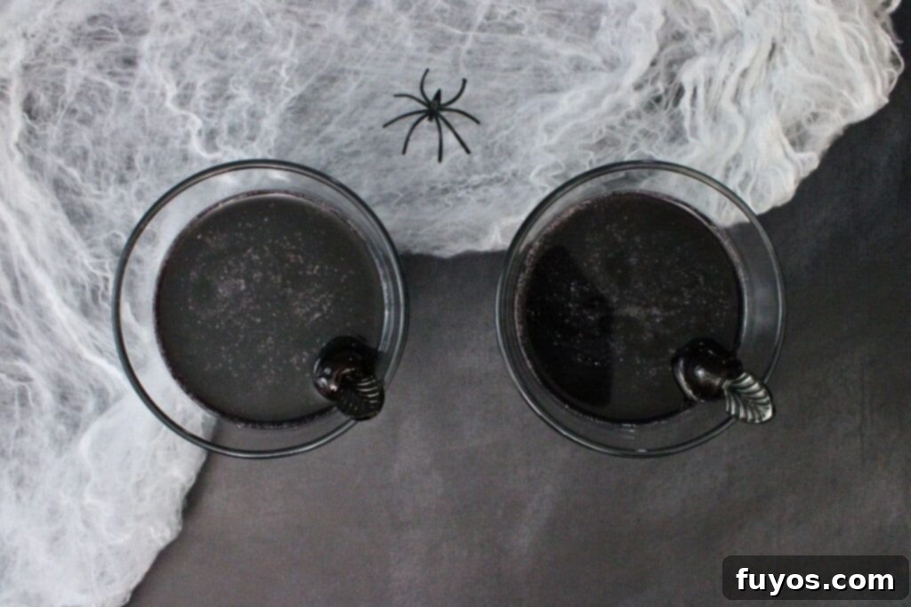 Black Magic Martini: Halloween's Darkest Spell 7 overhead view of two black martini halloween cocktails on wispy spiderwebs