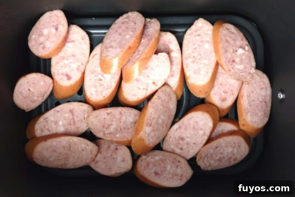 Adding slices of kielbasa in a single layer to a preheated air fryer basket