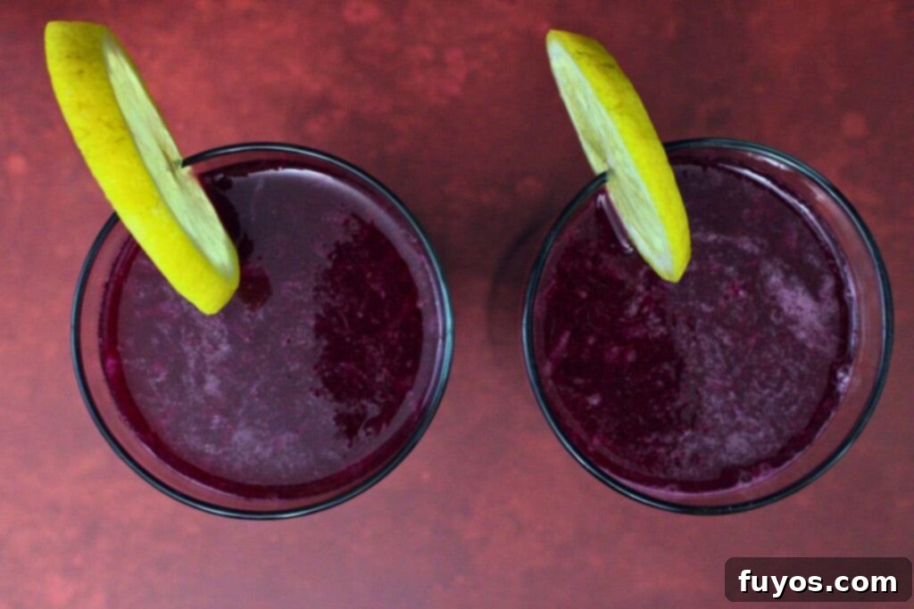 Easy Three Ingredient Beetroot Pomegranate Lemonade 8 overhead view of two beetroot pomegranate lemonade drinks garnished with lemon