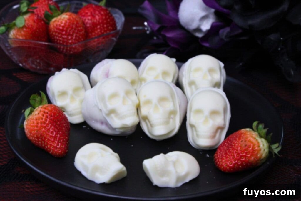 white chocolate strawberry skulls on a plate with fresh strawberries and pure chocolate skulls
