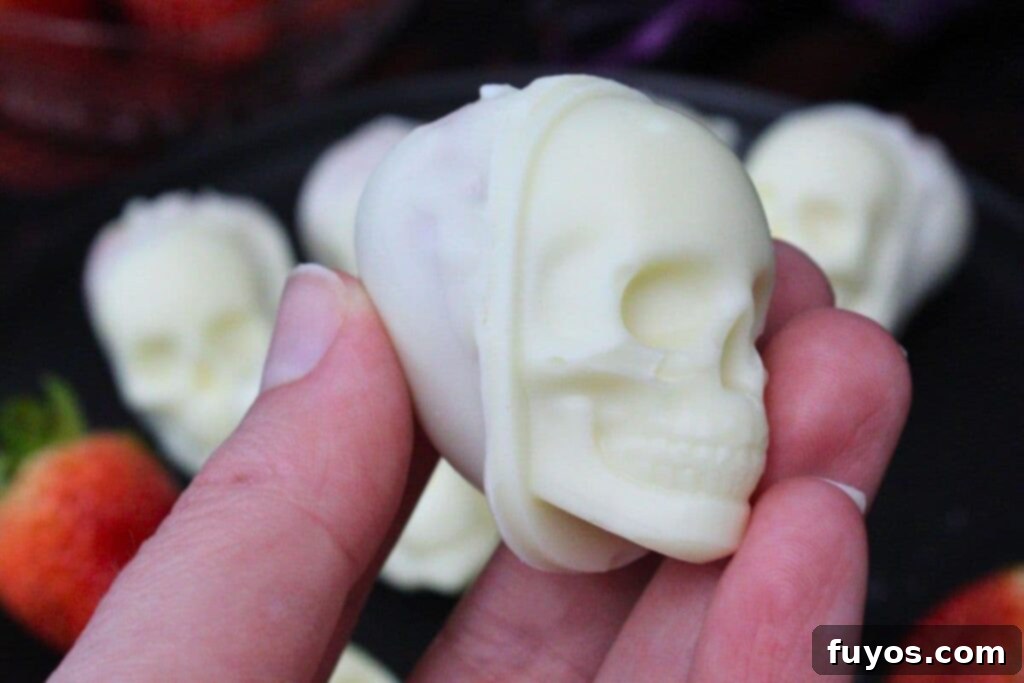 holding up a white chocolate covered strawberry skull