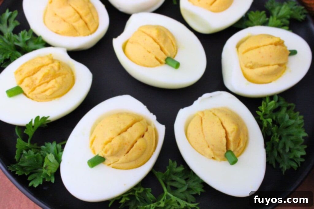 pumpkin deviled eggs made in the air fryer spread across a black plate