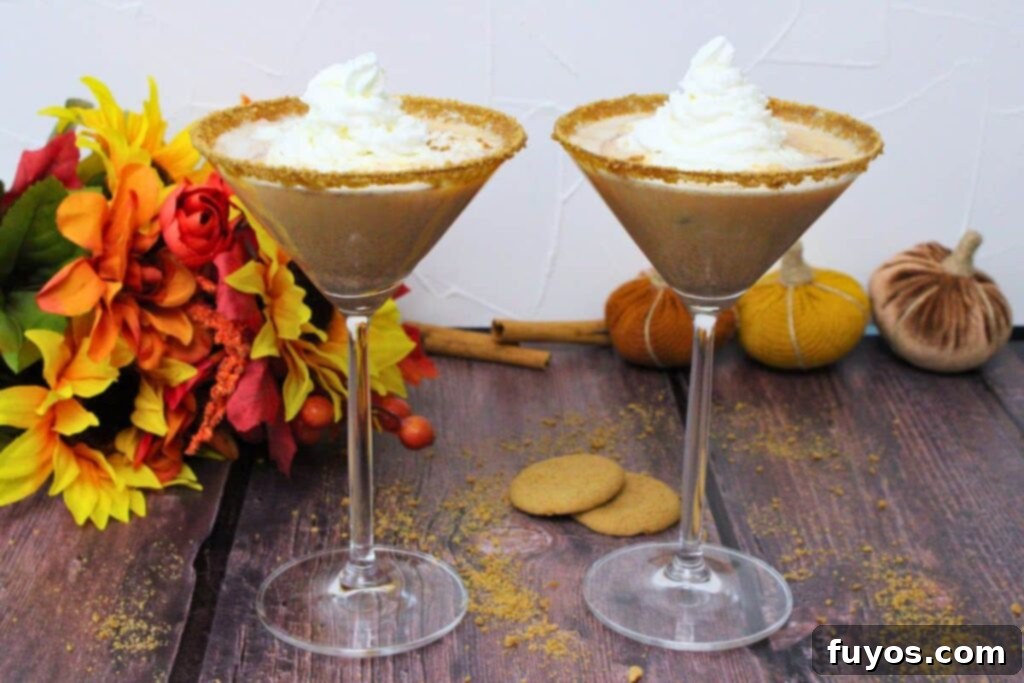 two pumpkin pie martinis with a swirl of whipped cream on a rustic background