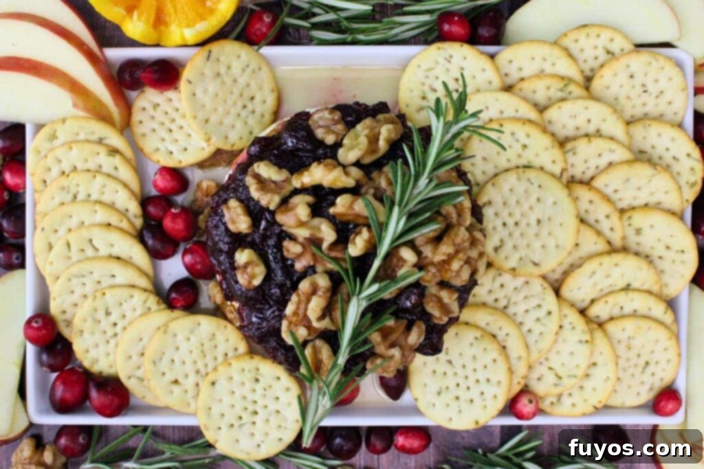 Air Fryer Cranberry Walnut Baked Brie 10 overhead view of cranberry baked brie on a platter of crackers, fresh cranberry, and rosemary