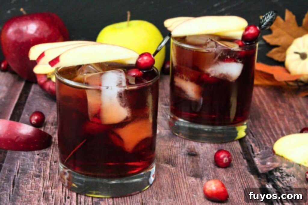 Crownberry Apple Two Ingredient Autumn Delight 3 Two festive Crownberry Apple drinks with apple slices and cranberries, set against a cozy fall backdrop, perfect for holiday entertaining.