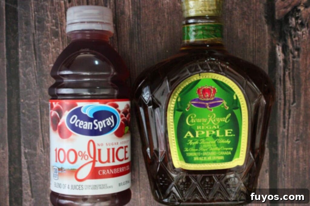 Crownberry Apple Two Ingredient Autumn Delight 4 Essential ingredients for making a Crownberry Apple cocktail: Crown Royal Apple whisky and cranberry juice on a rustic surface.