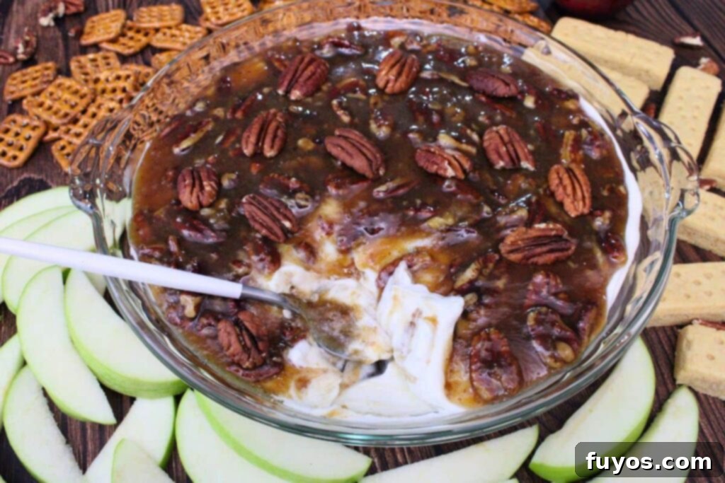pecan pie dip with a spoon in the serving dish surrounded by apple slices and pretzels