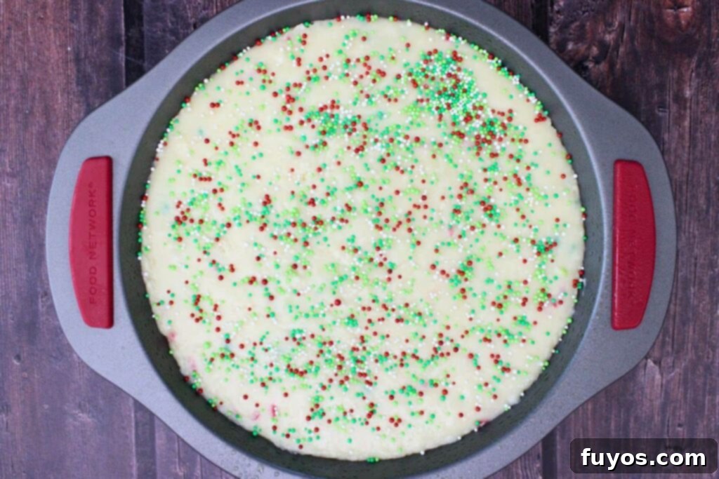 Easy Microwave Christmas Sugar Cookie Fudge Treat 8 Pouring sugar cookie fudge into a pan and adding sprinkles