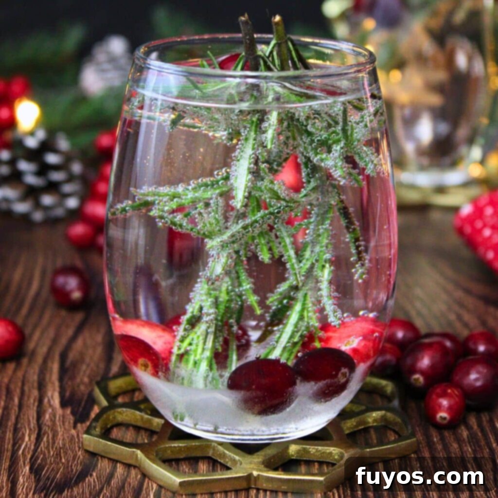 A dazzling Snow Globe Cocktail featuring frozen cranberries and rosemary, perfect for festive holiday celebrations.