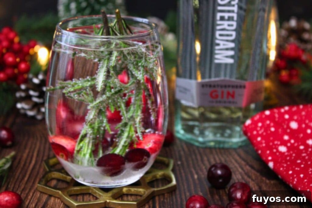 A festive Snow Globe Cocktail sits beside a bottle of gin, ready for holiday celebrations.