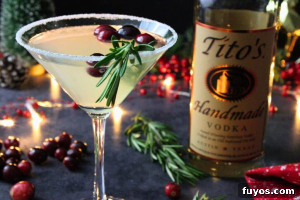 Close-up of a festive Christmas Lemon Drop Cosmo next to a vodka bottle, highlighting the beautiful garnish and sugar rim.