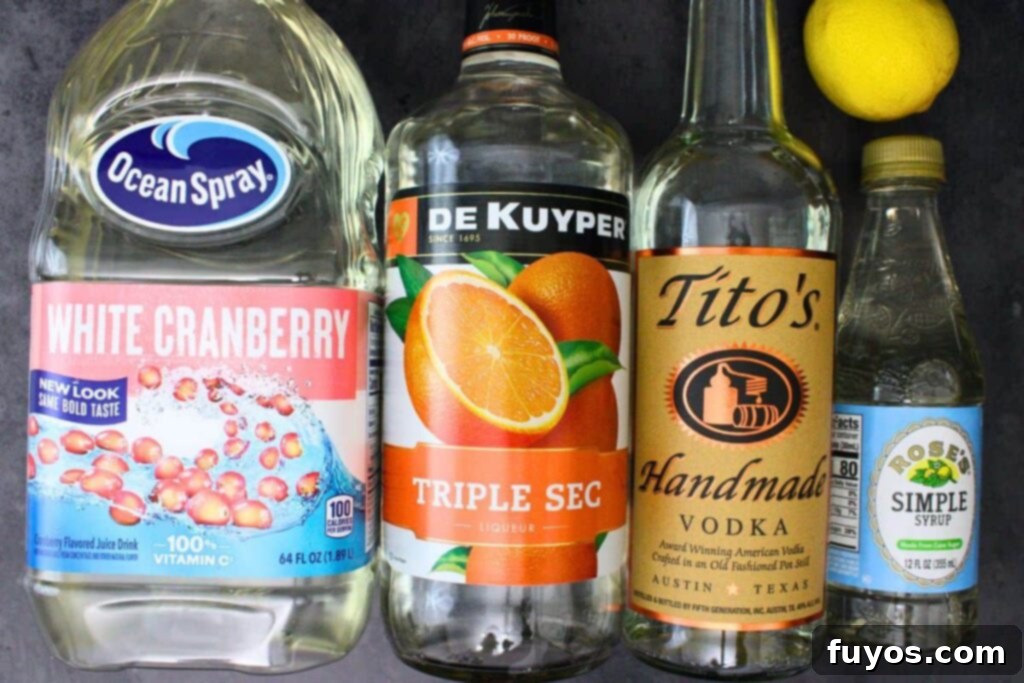Ingredients laid out for making a Christmas Lemon Drop Cosmo, including vodka, lemons, triple sec, and white cranberry juice.