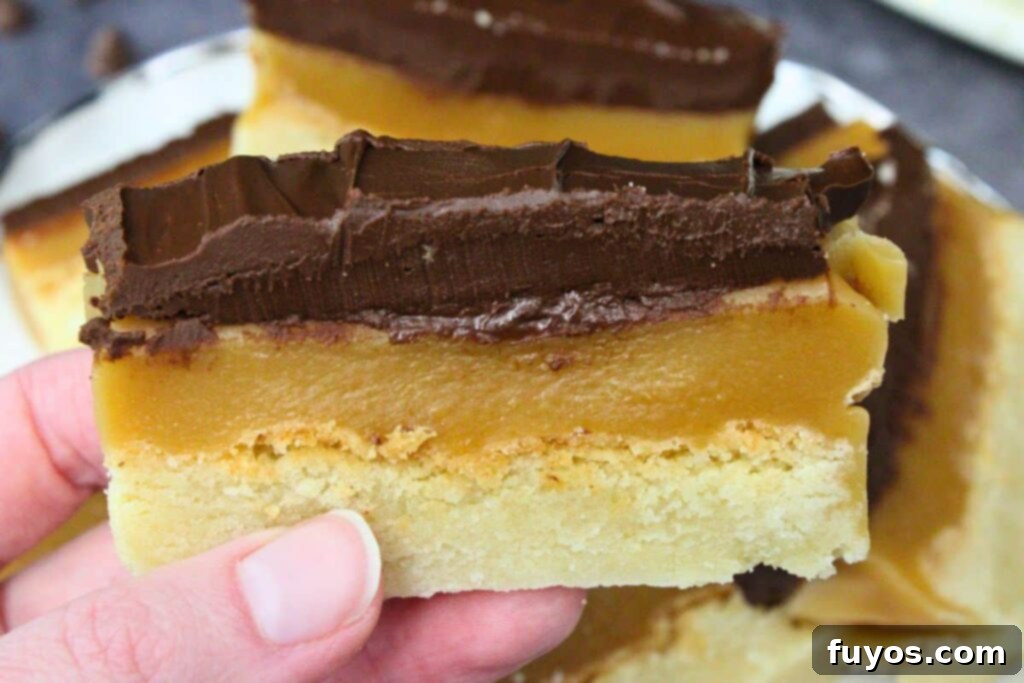 holding up a slice of air fryer millionaire shortbread showing chocolate and caramel layers