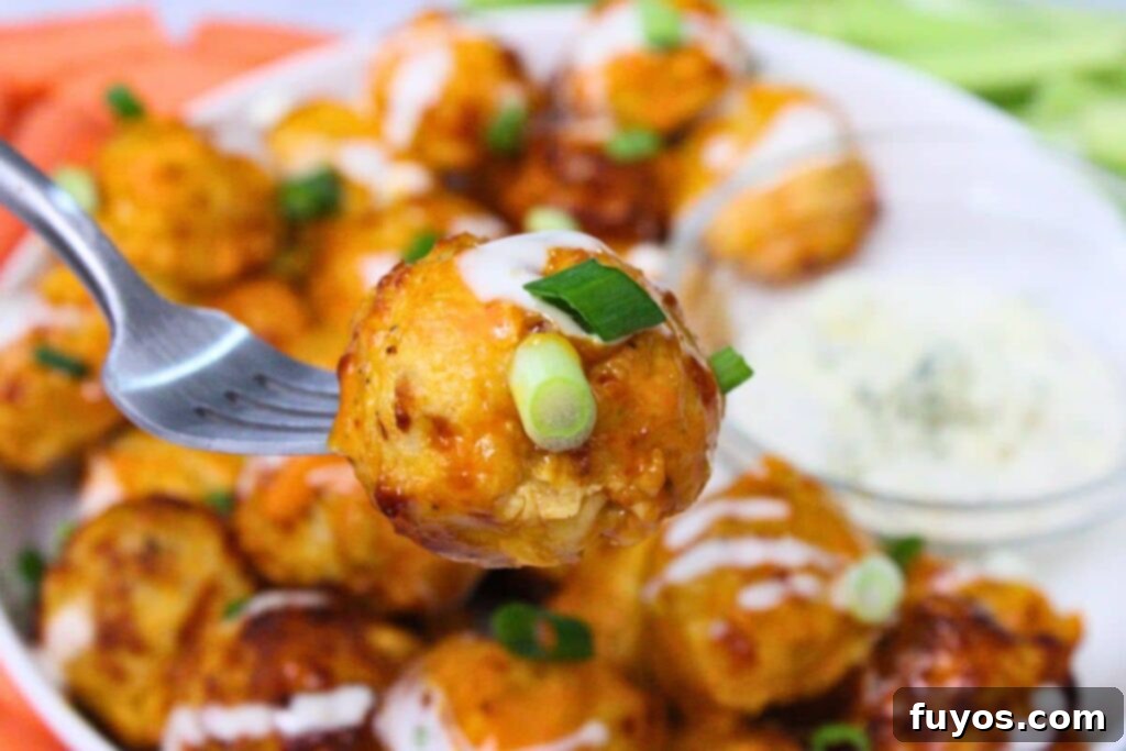 Close-up of an air fryer buffalo chicken meatball on a fork, showing its juicy interior and crispy exterior, ready to be enjoyed.