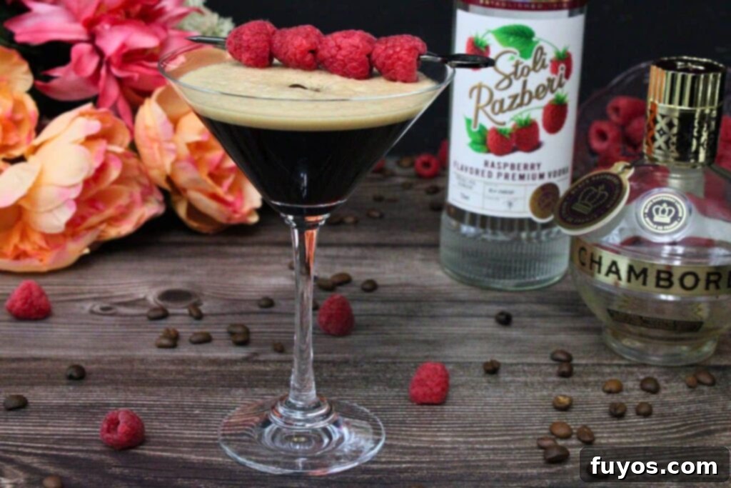 Chambord Raspberry Espresso Martini Made Easy 3 Ingredients for a Raspberry Espresso Martini laid out on a wooden table, including a martini glass, vodka bottle, and Chambord liqueur, highlighting the simplicity of preparation.