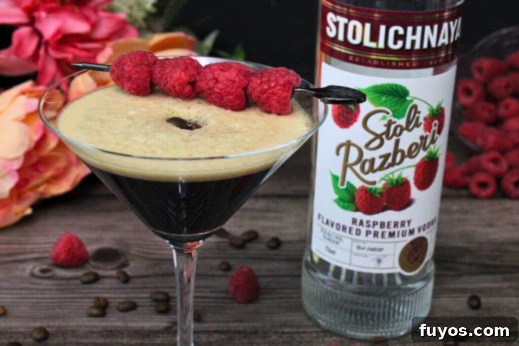 Chambord Raspberry Espresso Martini Made Easy 8 Close-up shot of a Raspberry Espresso Martini with fresh raspberries and a vodka bottle in the background, showcasing the vibrant color and elegant garnish.