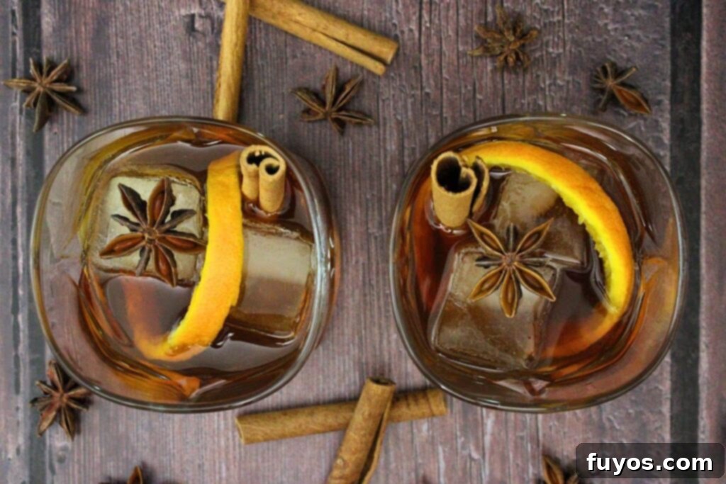 Chai Old Fashioned: The Warm Spice Bourbon 7 overhead view of two chai old fashioned with orange peel, cinnamon stick, and star anise on a wood table