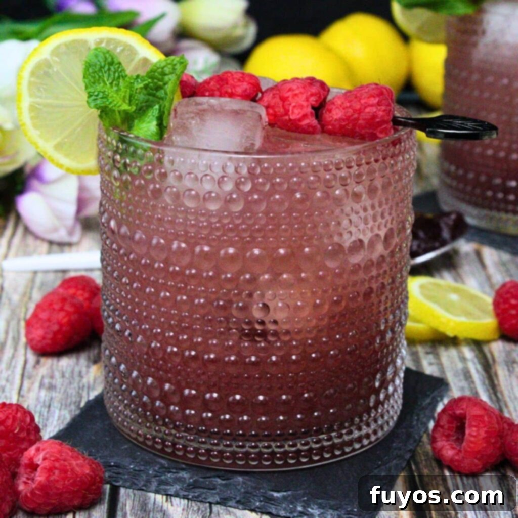 A vibrant Gin and Jam cocktail, garnished with fresh berries and a lemon slice, perfect for spring or summer enjoyment.