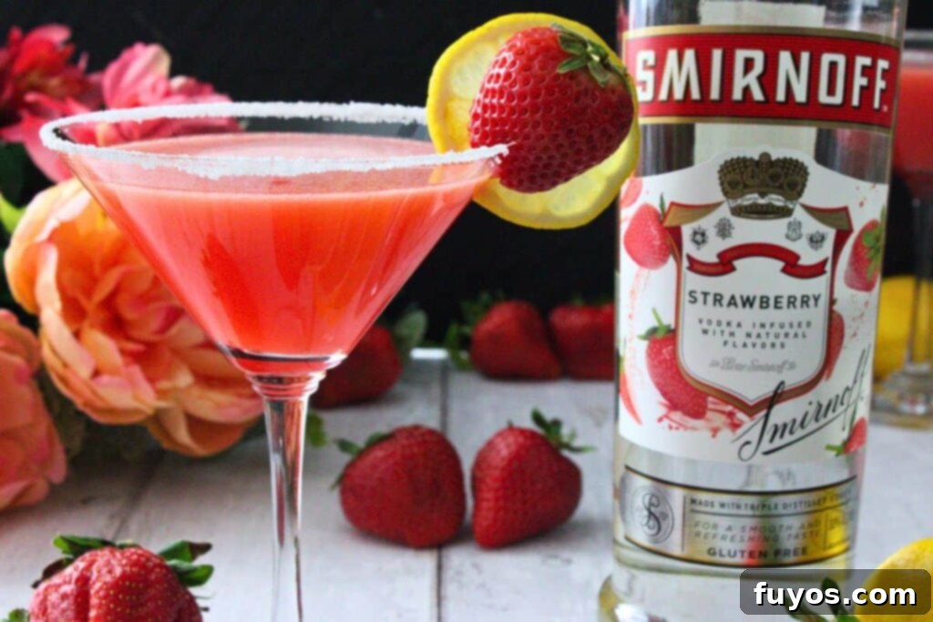 Strawberry lemon drop martini next to a bottle of vodka and fresh fruit, highlighting the key ingredients.