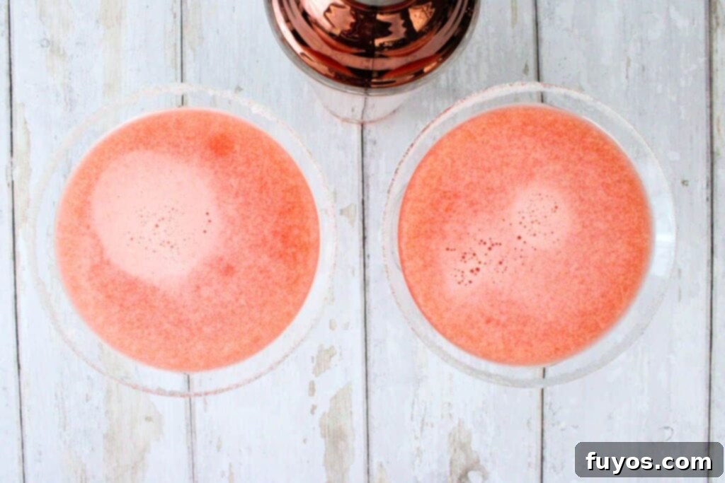 The final step of shaking the strawberry lemon drop cocktail until thoroughly chilled, then straining it into the prepared martini glasses.
