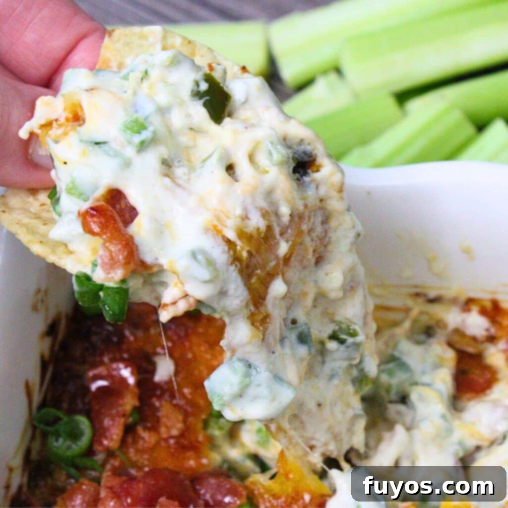 Creamy, cheesy jalapeno popper dip with bacon, ready to be scooped with dippers.