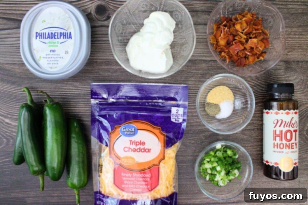 All the fresh ingredients laid out for making the jalapeno popper dip: cream cheese, sour cream, bacon, jalapenos, cheddar, garlic powder, green onion, and hot honey.
