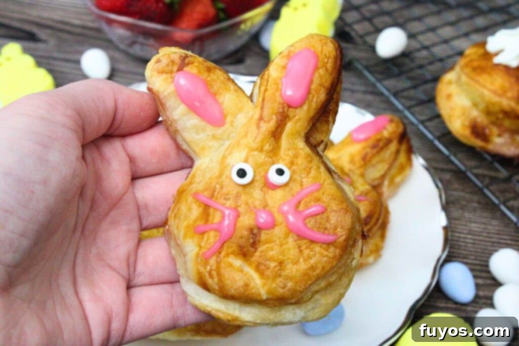Cute Easter Air Fryer Puff Pastry Bunnies 12 holding up a puff pastry bunny with googly eyes and a frosting nose
