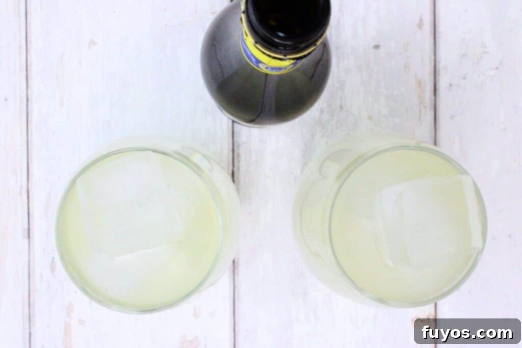 Zesty Sparkling Vodka Lemonade 6 Step-by-step image showing prosecco being poured to top off the vodka lemonade in a glass.