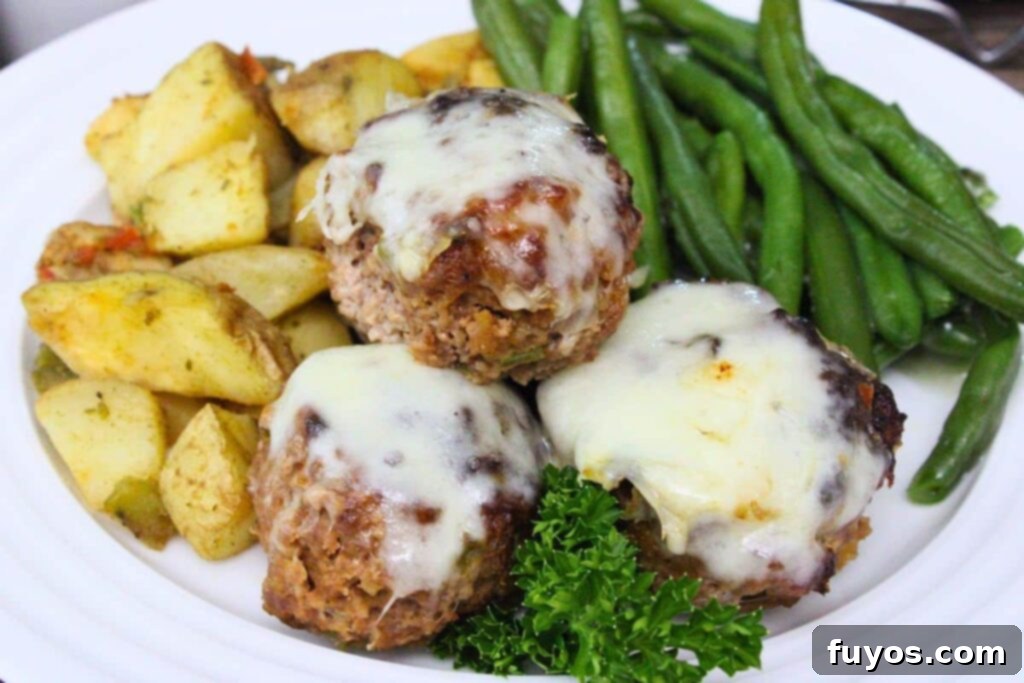 three philly cheesesteak meatloaf muffins on a plate with potatoes and green beans