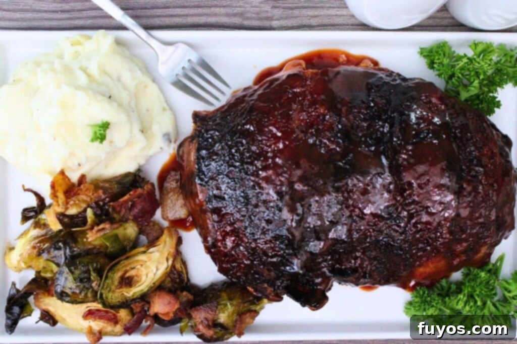 Bacon Wrapped Cheesy Stuffed Meatloaf Air Fryer Oven 10 overhead view of bacon wrapped meatloaf on a platter with mashed potatoes and bacon brussel sprouts
