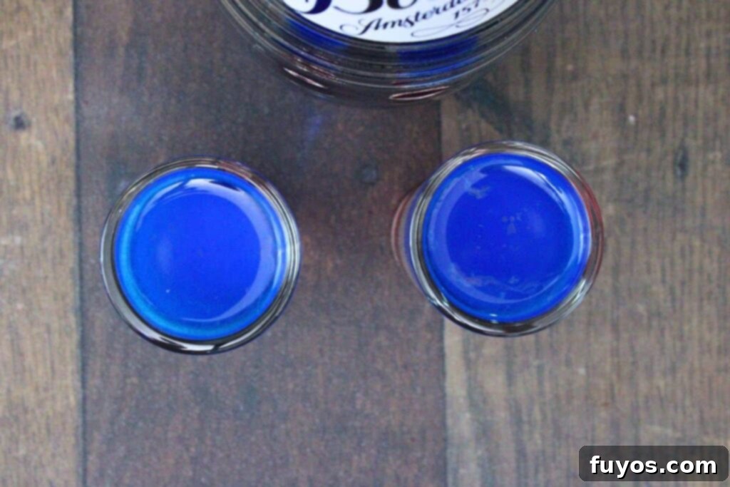 Stacked Red White Blue Party Shots 7 pour blue curacao over a spoon on top of white and red layers
