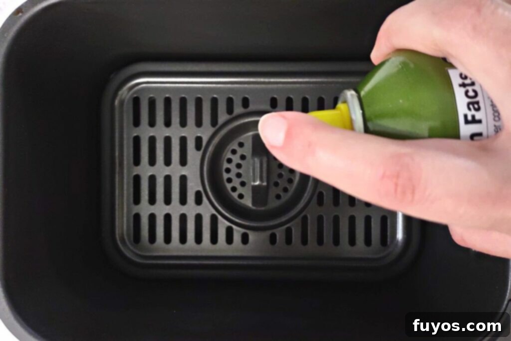 Air Fryer Frozen Fish Crispy and Quick 4 hand spraying oil in air fryer basket