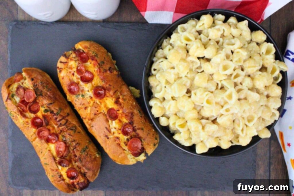 Pizza Hot Dogs: Your Go-To 30-Minute Flavor Fusion 9 over head view of two pizza hot dogs with mini pepperoni next to bowl of mac and cheese on a slate board