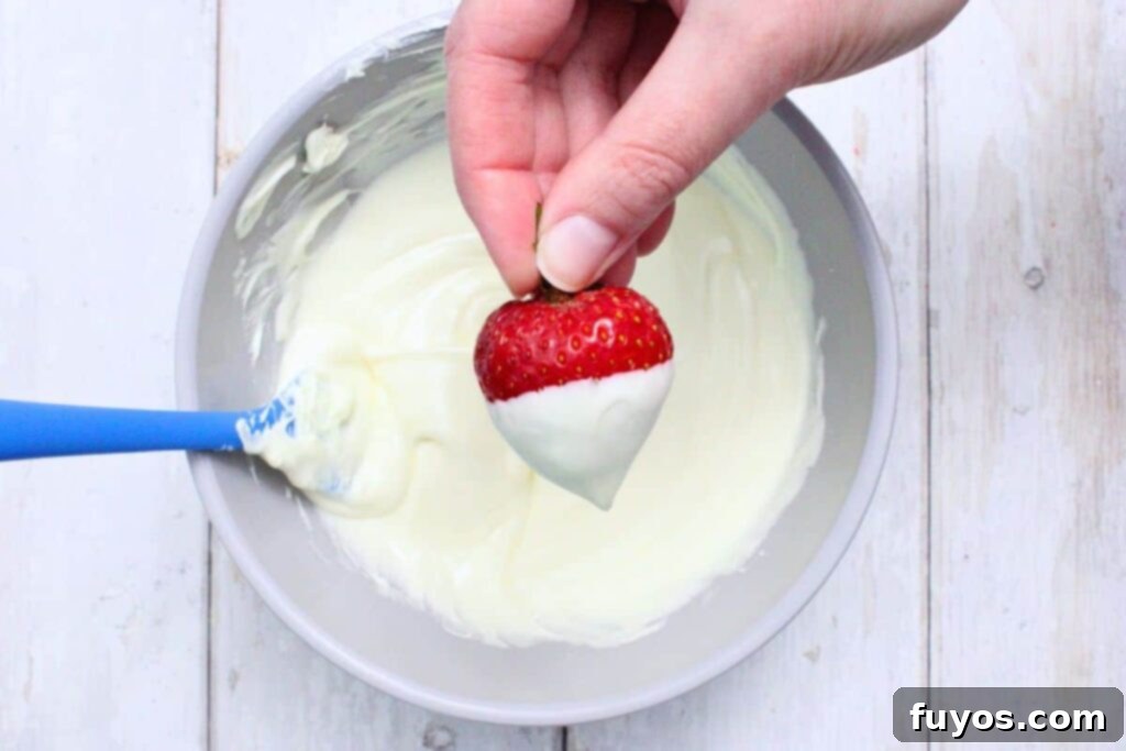 grab strawberry by leaves and dip into melted white chocolate