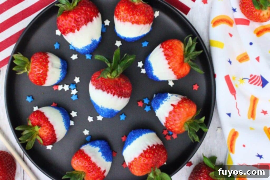 overhead view of red white and blue strawberries circling a black plate with festive star sprinkles