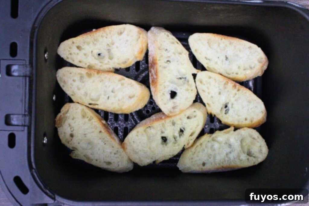 Arranging baguette slices in a single layer in the air fryer basket for crostini