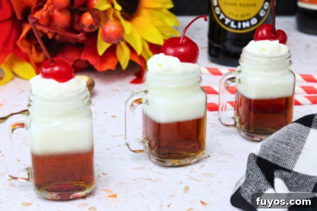 Grown-Up Root Beer Float Shots: A Sip of Summer Nostalgia 8 three root beer float shots in a line topped with whipped cream and a cherry