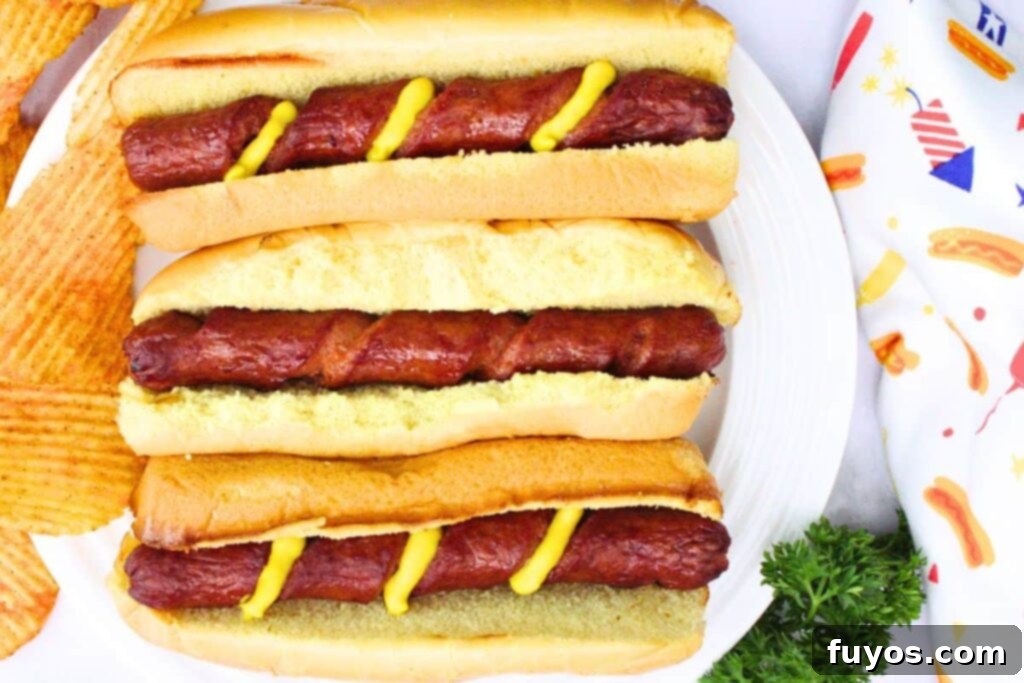 Air Fryer Crispy Spiral Hot Dogs 9 overhead view of three spiral hot dogs in buns laid vertically with mustard in the spiral cuts