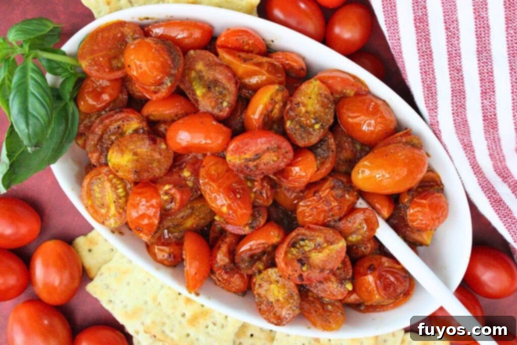 overhead view of a dish filled with air fryer cherry tomatoes and a serving spoon plus crackers