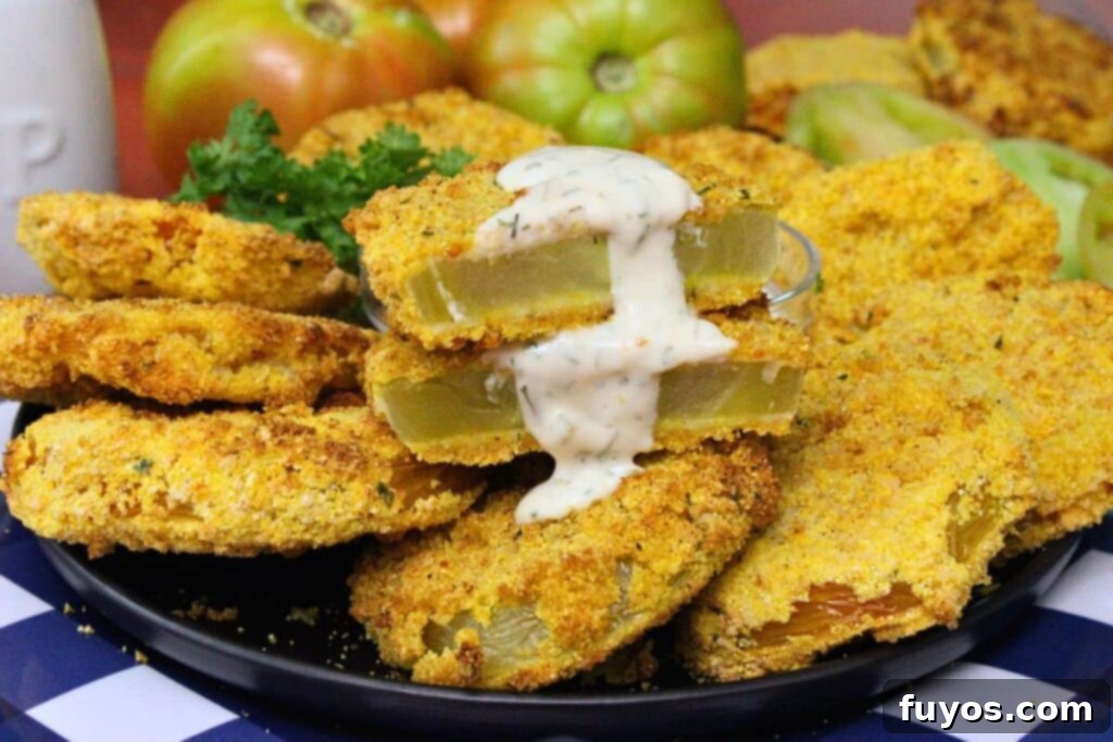 Golden Air Fryer Green Tomatoes with Irresistible Hot Honey Ranch 11 closeup view of air fryer fried green tomatoes on a plate with one cut in half dripping with hot honey ranch