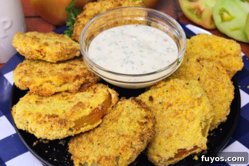 Golden Air Fryer Green Tomatoes with Irresistible Hot Honey Ranch 3 air fryer fried green tomatoes on a plate circling a bowl of hot honey ranch sauce